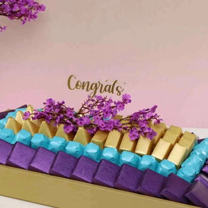 صينية شوكولاتة مزينة بأزهار الكرز مع تشكيلة فاخرة من الشوكولاتة flowerna