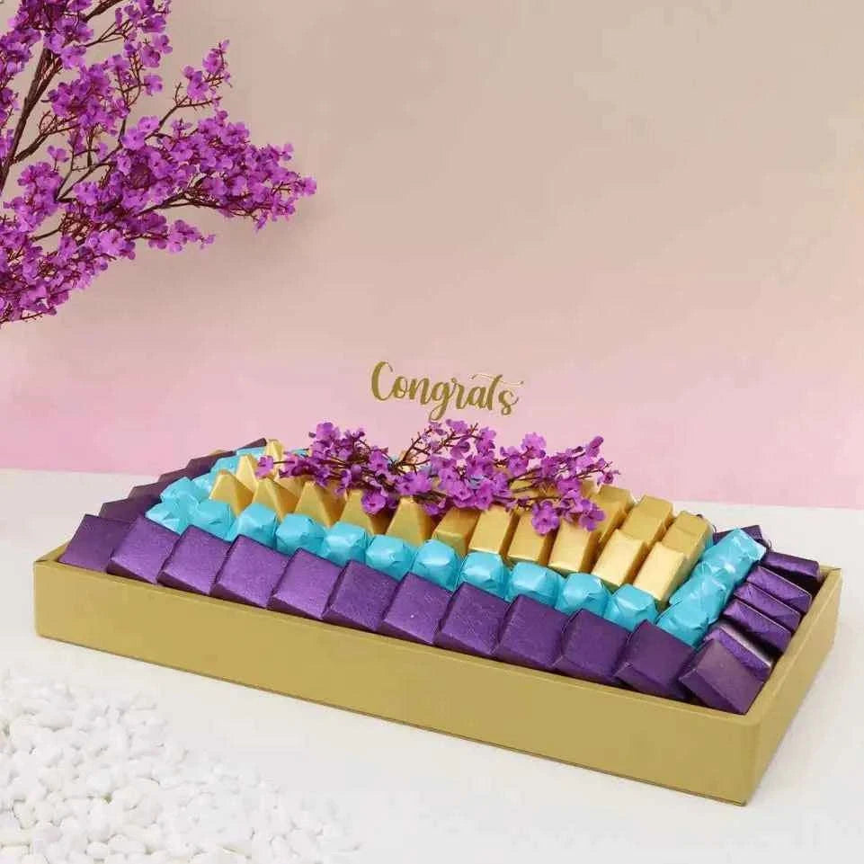 صينية شوكولاتة مزينة بأزهار الكرز مع تشكيلة فاخرة من الشوكولاتة flowerna